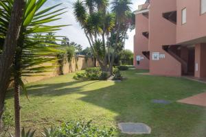 un patio con palmeras y un edificio en Apartamento Pink Mariposas en Chiclana de la Frontera