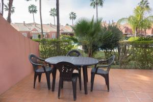 a table and four chairs on a patio with palm trees at Apartamento Pink Mariposas in Chiclana de la Frontera