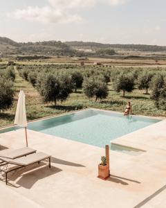 a woman is standing next to a swimming pool in a field at Agroturisme Gossalba in Sant Joan