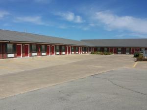 un grand bâtiment avec des portes rouges dans un parking dans l'établissement Green Country Inn, à Henryetta