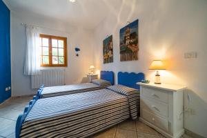 two beds in a bedroom with blue and white walls at Villa Medina - Goelba in Porto Azzurro