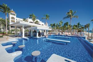 a swimming pool at a resort with palm trees at Riu Palace Cabo San Lucas - All Inclusive in Cabo San Lucas