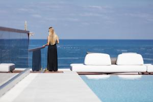 a woman standing on a podium next to a swimming pool at Zillion Villa, intangible beachfront luxury, By ThinkVilla in Panormos Rethymno
