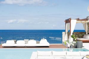 einen Pool mit weißen Möbeln und Meerblick in der Unterkunft Zillion Villa, intangible beachfront luxury, By ThinkVilla in Panormos