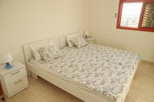 a bedroom with a white bed with pillows and a window at valentine House in Deir Ḥannā