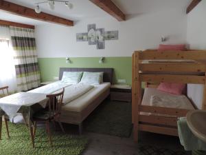 a bedroom with a bunk bed and a table and chairs at Tatscherhof in Hainzenberg