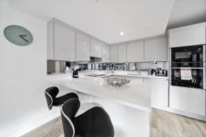 a large white kitchen with black chairs and a clock at Executive Apartments in Bermondsey FREE WIFI & AIRCON by City Stay Aparts London in London