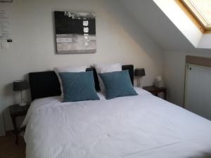 a bedroom with a white bed with two blue pillows at B&B 't Hemelbedje in Nieuwpoort