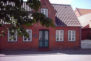 ein rotes Backsteinhaus mit einer schwarzen Tür in der Unterkunft Amrum in Wyk auf Föhr