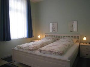 een bed in een slaapkamer met een raam en 2 lampen bij Gästehaus Hoferichter, Whg 1 in Wyk auf Föhr