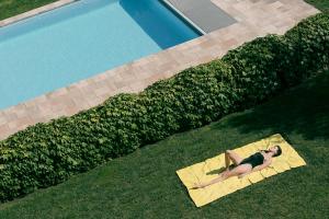 a woman laying on a yellow towel next to a swimming pool at Can Alemany in Santa Margarita de Mombúy