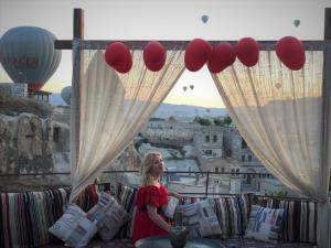 una mujer parada en un balcón con globos rojos en Antique Terrace Cave Suites en Goreme