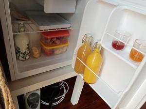 an open refrigerator with two bottles of orange juice at Wee Hoose Glaping Pod 2 in Skail