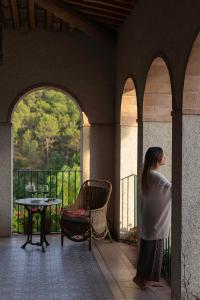 a woman standing on a porch looking at a table at Can Alemany in Santa Margarita de Mombúy