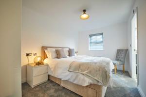 a white bedroom with a bed and a chair at Host & Stay - Potters Bank in Durham