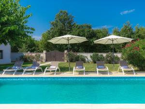 a group of chairs and umbrellas next to a pool at Holiday Home Tijan - ROJ411 by Interhome in Žminj