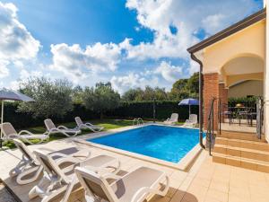 a swimming pool with white chairs and a table at Holiday Home Lara by Interhome in Vrsar