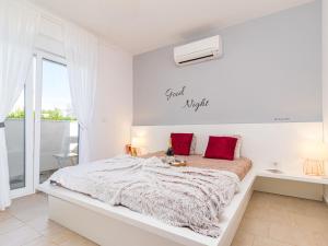 biała sypialnia z dużym łóżkiem z czerwonymi poduszkami w obiekcie Holiday Home Villa Virtus by Interhome w mieście Brtonigla