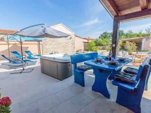 eine Terrasse mit einem blauen Tisch, Stühlen und einem Sonnenschirm in der Unterkunft Apartment Botra Maria - ROJ458 by Interhome in Sveti Petar u Šumi