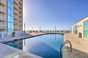 a swimming pool next to a building and the ocean at Sunny Beachfront Biloxi Condo with Resort Amenities! in Biloxi