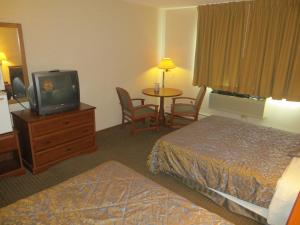 Habitación de hotel con cama, TV y mesa. en Ripon Welcome Inn and Suites, en Ripon