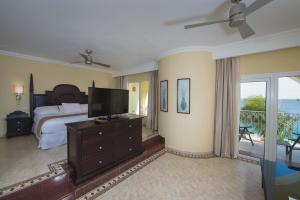 a bedroom with a bed and a television and a balcony at Riu Palace Cabo San Lucas - All Inclusive in Cabo San Lucas