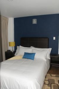 1 cama blanca grande con pared azul en Suites Berna 12, en Ciudad de México