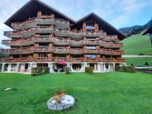 a large building with a green lawn in front of it at Appartement et studio, Val d'illiez in Val-d'Illiez