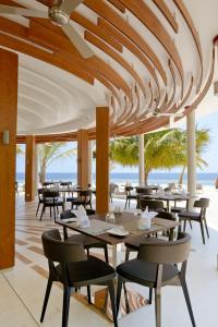 a dining room with tables and chairs and umbrellas at Kandolhu Maldives in Himandhoo 