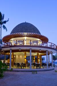 a circular building with tables and chairs on the beach at Kandolhu Maldives in Himandhoo 
