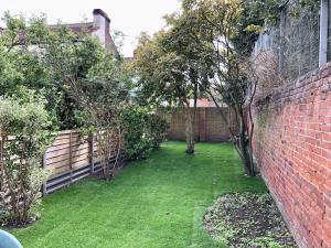 a garden with a brick wall and trees and grass at Purple Cloud Cosy 4 bed Cottage with Garden Parking Pet-Friendly in Portsmouth