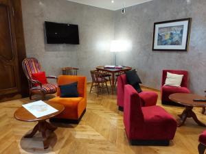a waiting room with chairs and tables and a flat screen tv at Hôtel La Montagne Fleurie in Barèges