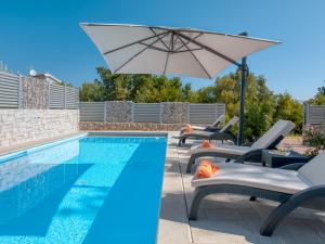 een zwembad met stoelen en een parasol naast een zwembad bij Holiday Home Lavendel - MLK159 by Interhome in Dobrinj