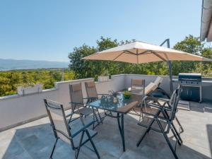 een patio met een tafel en stoelen en een parasol bij Holiday Home Lavendel - MLK159 by Interhome in Dobrinj