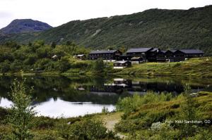 a house on the side of a river with mountains at Jotunheimen Fjellstue in Boverdalen