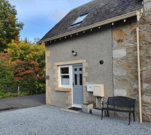 un edificio con una puerta azul y un banco fuera en Oakbank Cottage, en Pitlochry