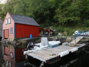 un bateau sur un quai à côté d'un bâtiment rouge dans l'établissement Holiday Home Rødehuset - FJH670 by Interhome, à Gjelland