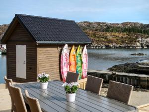 un tavolo in legno con sedie e tavole da surf su una casa di Holiday Home Brosme - FJH103 by Interhome a Bømlo
