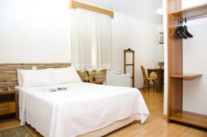 a bedroom with a white bed and a table at Millian Hotel in Jundiaí