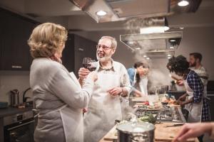 a man and woman in a kitchen with a glass of wine at Is Cheas wine farm boutique hotel in San Vero Milis