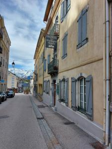 an empty street in a town with buildings and mountains at Hôtel La Montagne Fleurie in Barèges