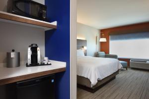 a hotel room with a bed and a tv on a wall at Holiday Inn Express & Suites Spring - Woodlands Area by IHG in Spring +47 photos