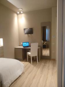 a bedroom with a bed and a desk with a laptop at Albergo Ristorante Palladio Osteria dal 1900 in Fratta Polesine