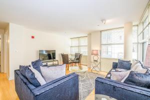 a living room with two blue couches and a tv at Evonify Stays - Theatre District Apartments in Boston