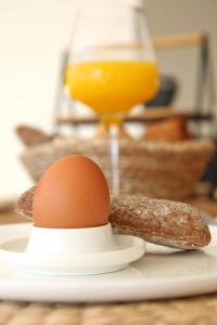 an egg on a plate with a sausage and an orange juice at Casa Bodhi Boutique Hotel & Spa in Marbella