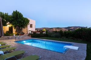 a swimming pool in a yard with chairs around it at Antheon - Three Bedroom Villa with Private Pool in Áno Valsamóneron