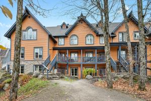 a large wooden house with trees in front of it at Le Manoir 106-7 by Escapades Tremblant in Mont-Tremblant