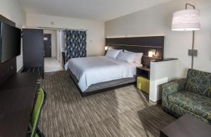Holiday Inn Express & Suites - Saskatoon East - University, an IHG Hotel في ساسكاتون: غرفه فندقيه بسرير واريكه