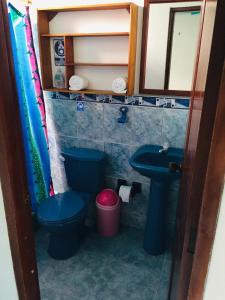 a bathroom with a blue toilet and a sink at Hospedaje Sarita in Puerto Villamil