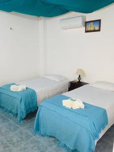 2 camas en una habitación de color azul y blanco en Hospedaje Sarita, en Puerto Villamil